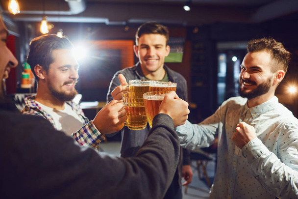 Friends clinking beer mugs in bar - Photo, image
