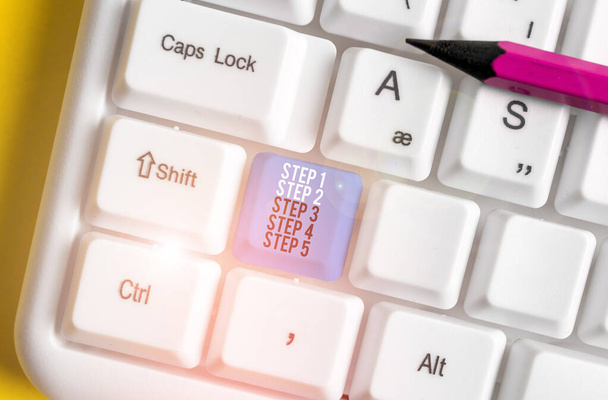 konzeptionelle Handschrift mit den Schritten 1, 2, 3, 4 und 5. Geschäftsfoto, das die Stufen eines Prozessablaufs zeigt, weiße PC-Tastatur mit Notizpapier über weißem Hintergrund. - Foto, Bild
