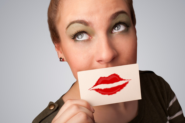 Happy pretty woman holding card with kiss lipstick mark - Фото, изображение