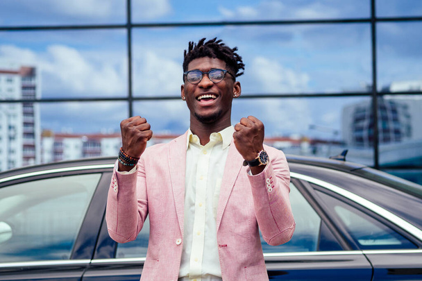 happy and successful afro american businessman rejoices and enjoying success ahead of the car. concept of a good deal and victory - Foto, imagen