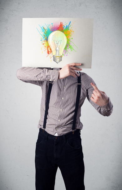 Businessman holding a cardboard with paint splashes and lightbul - Фото, зображення