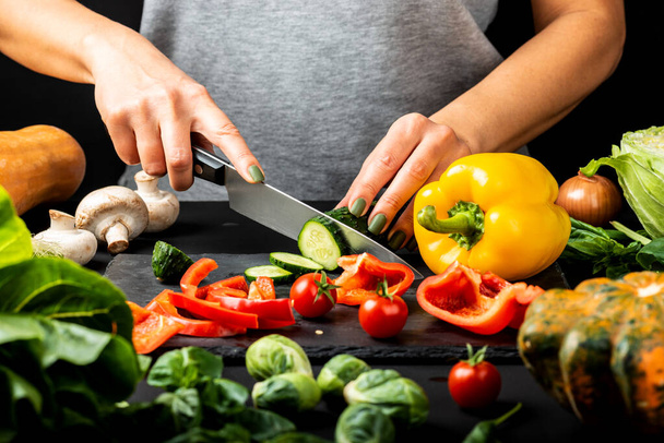 Las manos femeninas preparan la comida vegetariana, cortan hortalizas diferentes. Concepto de dieta saludable
. - Foto, imagen