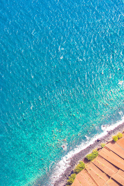 Aerial photography of the turquoise Atlantic ocean coast in Madeira, Portugal. Stone beach and adjacent fields on the southern coast of the Portuguese island. Aerial view, seascape - 写真・画像