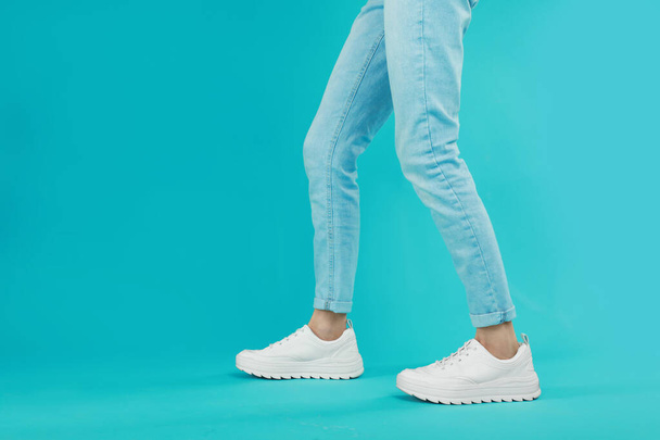 Woman in stylish sport shoes on light blue background. Space for text - Valokuva, kuva
