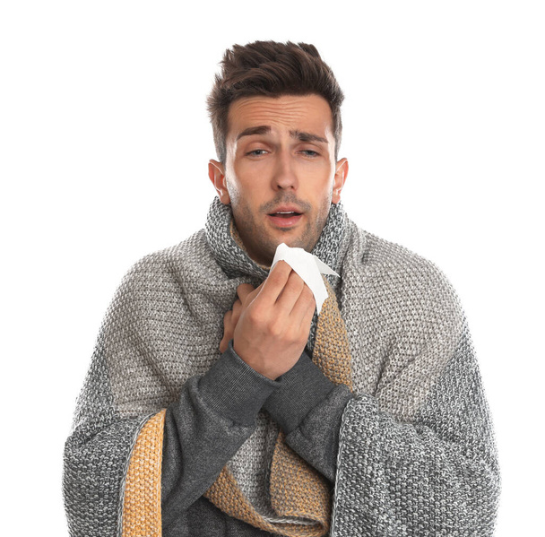 Young man wrapped in warm blanket suffering from cold on white background - Fotografie, Obrázek