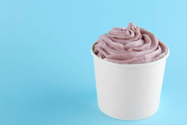 Cup with tasty frozen yogurt on blue background. Space for text - Φωτογραφία, εικόνα