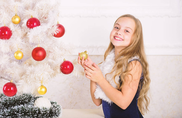 Kid cheerful excited about new year coming. Family holiday concept. Small girl wear velvet dress feels festive near christmas tree. Christmas very special time of year. Spread christmas cheer - 写真・画像