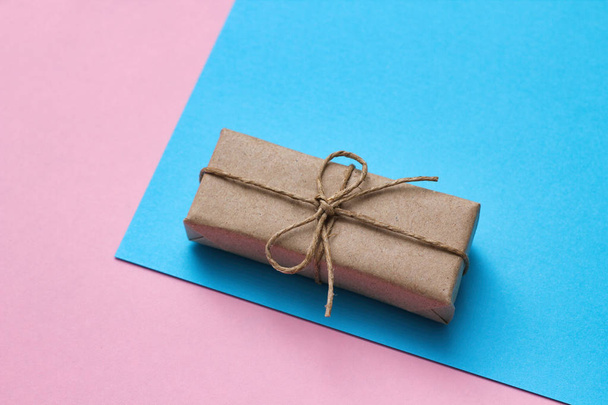 Gender determination day concept. Gift box wrapped in craft paper and tie hemp thread. Pink and blue backgrounds. Girl or boy. Birthday party.  - Фото, зображення