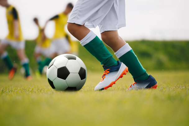 サッカー選手が野球場でボールを蹴ります。トレーニングセッションでサッカー選手。詳細サッカーの背景。緑の芝生の上でサッカー選手の足と足の閉鎖 - 写真・画像