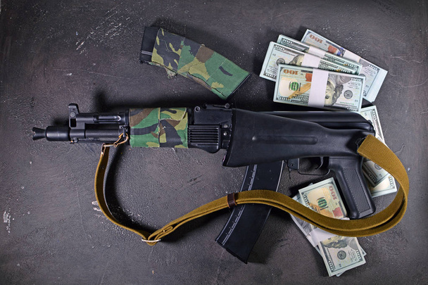 Weapon and money. A new assault Kalashnikov AK 74  M machine gun and dollar cash. Criminal news story background. - Fotó, kép