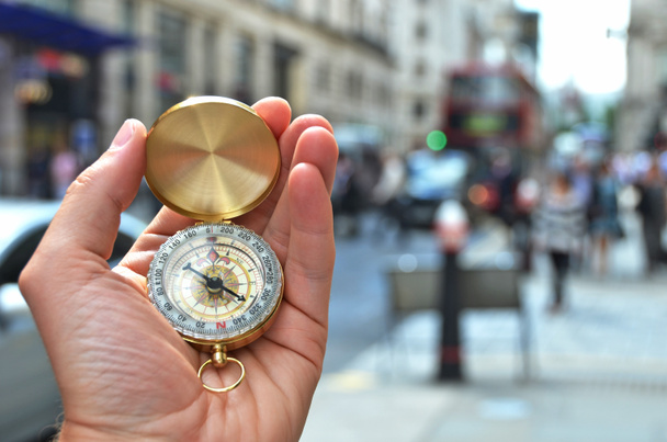 Compass in the hand against a city street - 写真・画像