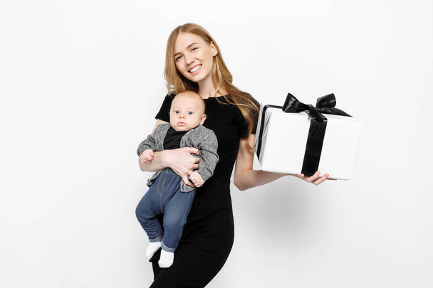Happy elegant young mom, girl in black dress, happily holding a  - Foto, imagen