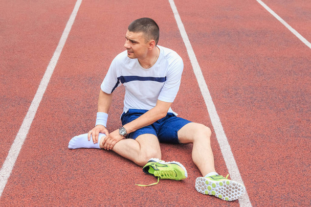 Jogger hands on foot. He is feeling pain as his ankle or foot is broken or twisted. Accident on running track during the morning exercise. Sport accident and foot sprain concepts. - Фото, изображение