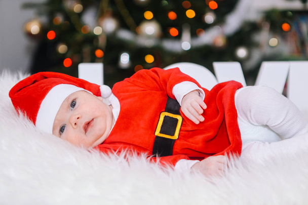 Beautiful newborn baby in Christmas costume celebrates Christmas - Fotó, kép