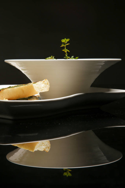 An exquisite minimalistic styled dish served in a bowl on black with reflexion. Creative restaurant meal concept. Haute couture food. Fine dining concept. - Фото, зображення
