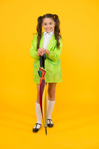 Childhood memories of playing in rain. Happy little child holding colorful umbrella on yellow background. Childhood activities on rainy autumn day. Childhood and school time. Enjoying happy childhood - Photo, Image