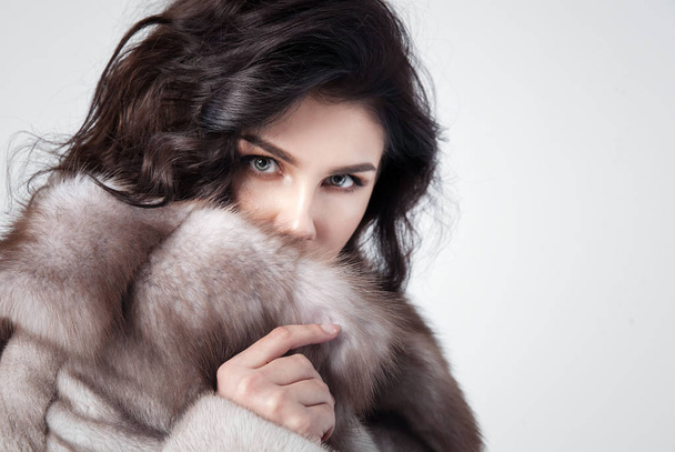 Beautiful elegant woman posing in luxury fashion fur coat over w - Фото, зображення