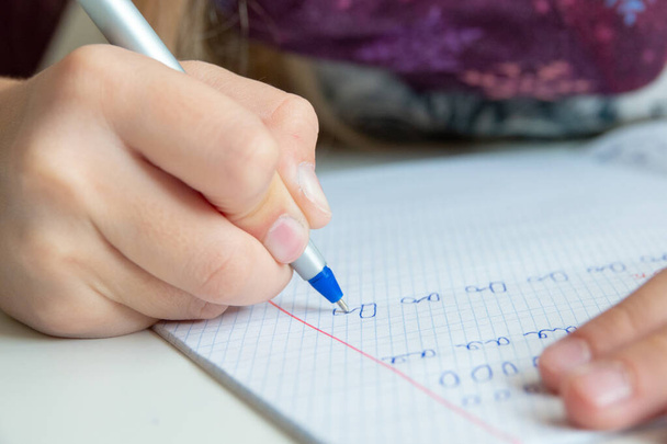 Un gamin tenant un stylo et écrivant dans un cahier. Gros plan
 - Photo, image