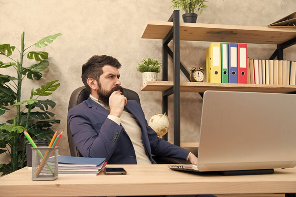 Responding on business e-mail. Brutal businessman in office. Mature man with beard work on laptop. bearded hipster use computer. Male boss working. Keeping business on top with digital technologies - 写真・画像