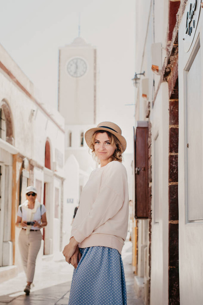 Santorini travel tourist woman on vacation in Oia walking on stairs. Person in white dress visiting the famous white village with the mediterranean sea and blue domes. Europe summer destination - 写真・画像