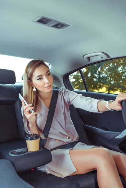 woman taxi, asks stop driver while driving, stop demand, communication driver, between passenger taxi driver. Business class, fashionable stylish business, summer spring, autumn, mobile phone, call. - Фото, зображення