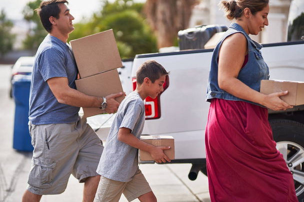 Испанская семья перевозит коробки из пикапа в дом
 - Фото, изображение