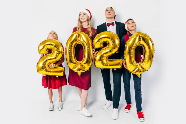 Young happy family with kids wearing Santa hats holding balloons - Foto, immagini