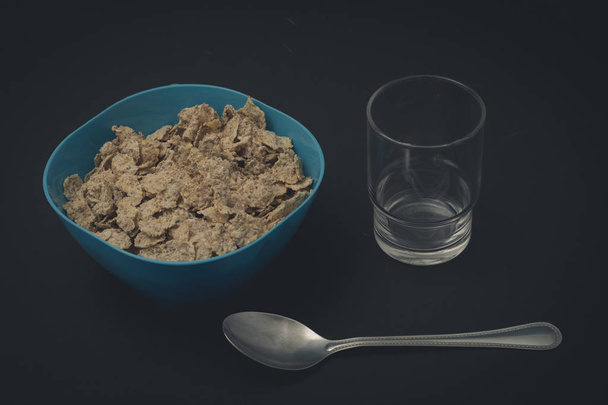 Cereal con una cuchara y un vaso en fondo negro - Foto, Imagem