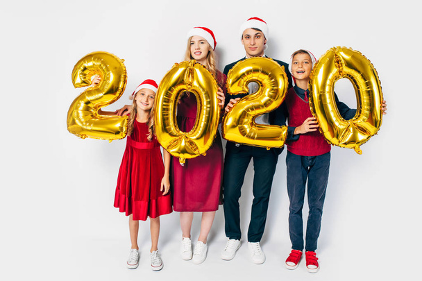 Young happy family with kids wearing Santa hats holding balloons - Φωτογραφία, εικόνα