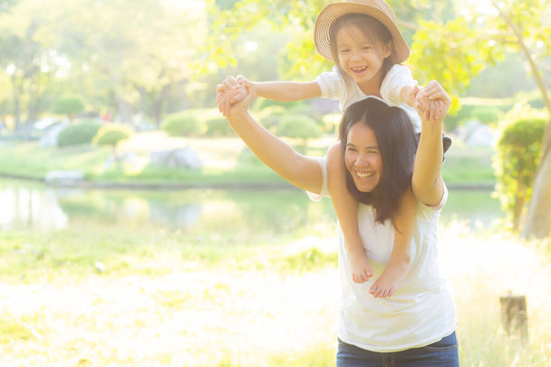 schöne junge asiatische Mutter trägt kleine Tochter mit Lächeln - Foto, Bild