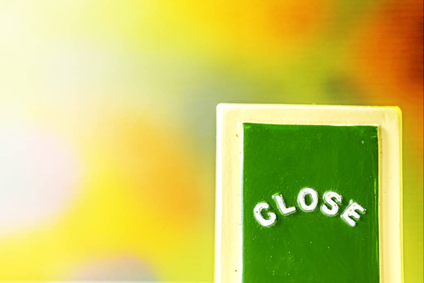 Close up of a green "CLOSE" chalkboard sign leaning against bright with black background. - Foto, imagen