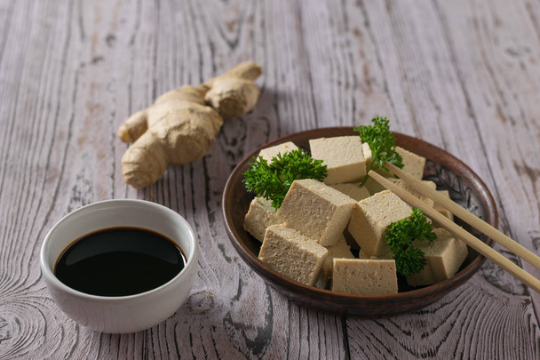 Tofukäse, Sojasauce und Ingwerwurzel auf einem Holztisch. Sojakäse. - Foto, Bild
