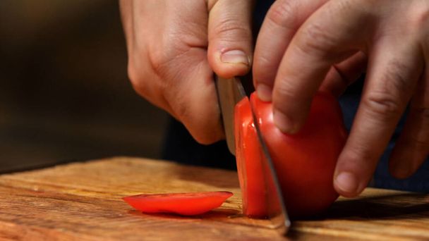 Cutting red tomato on wooden board. Stock footage. Chef cut tomato on a wooden Board - Zdjęcie, obraz
