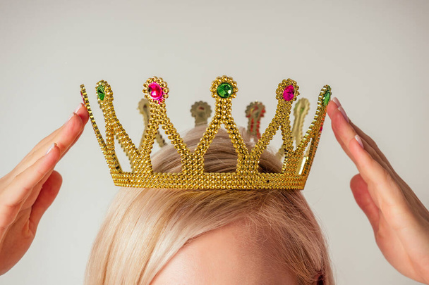 Beauty queen woman blonde put on placing tiara crown on head high self esteem selfishness studio white background - Photo, image