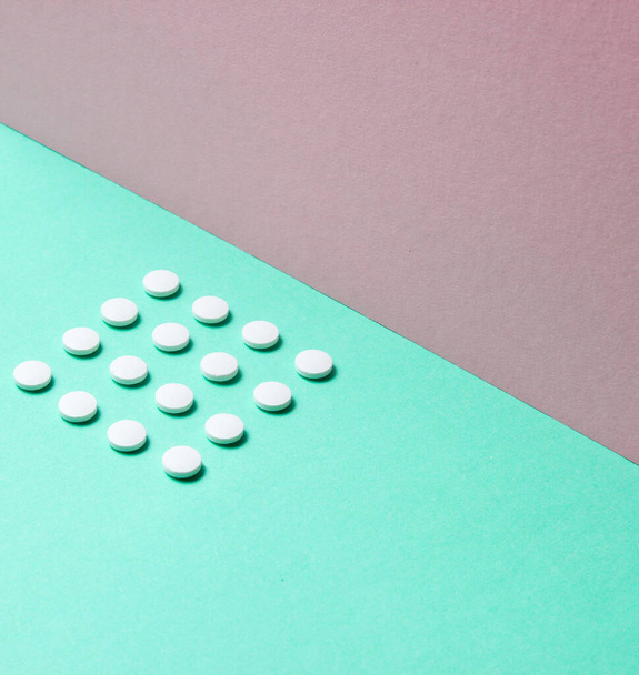 Minimalistic medical concept. Group of identical white tablets on a pastel colored background. Top view - Fotoğraf, Görsel