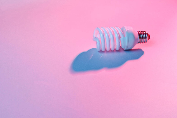 Spiral eco light bulb on neon light background. Minimalism concept - Photo, Image