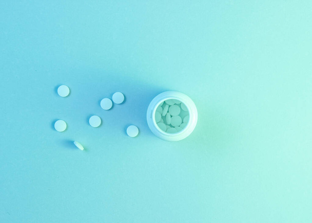 Минимализм медицинской концепции. Маленькая бутылка с антидепрессантами, белые таблетки, голографический голубой свет. Вид сверху - Фото, изображение