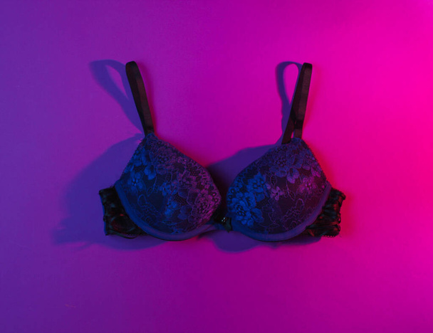 Erotic concept. Women's sexy bra, neon pink light. Top view - Photo, Image