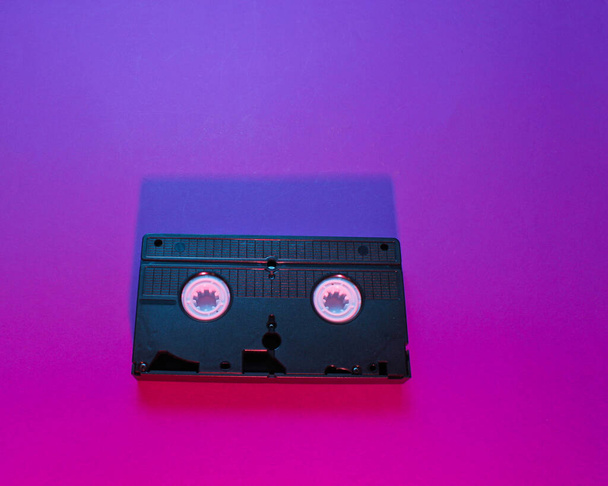 Cassette vidéo de style vague rétro avec lumière rose-violet néon. 80 ans. Vue du dessus
 - Photo, image
