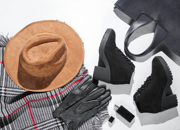 Autumn wardrobe. Women's things, shoes and accessories on a white background. Felt hat, suede boots, bag, leather gloves, bottle of perfume, scarf. Flat lay - Photo, Image