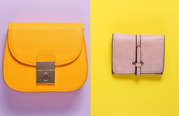 Fashion minimalism. Small yellow bag, leather wallet on a colored paper background. Top view - Photo, Image