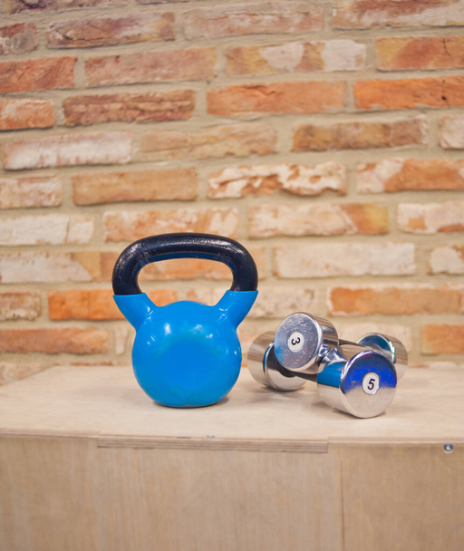 Functional training concept. Kettlebell, dumbbell stand on wooden box against the brick wall background.Functional training concept.Free weight training.  Workout equipment - Photo, Image