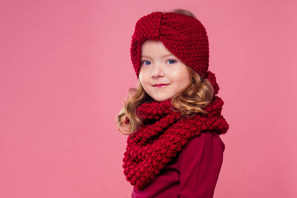 cute little girl in warm knitted colored hat on pink background in studio.Children winter clothes - 写真・画像
