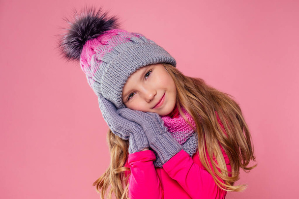 Cute little lady wearing woolen hat and scarf with mittens against tpink background on studio,autumn and winter fashion season well-dressed pretty child model dreaming - 写真・画像