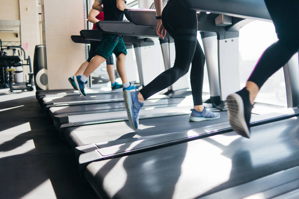 Group of people running on a treadmill. Cardio training for weight loss in the gym. - Fotó, kép
