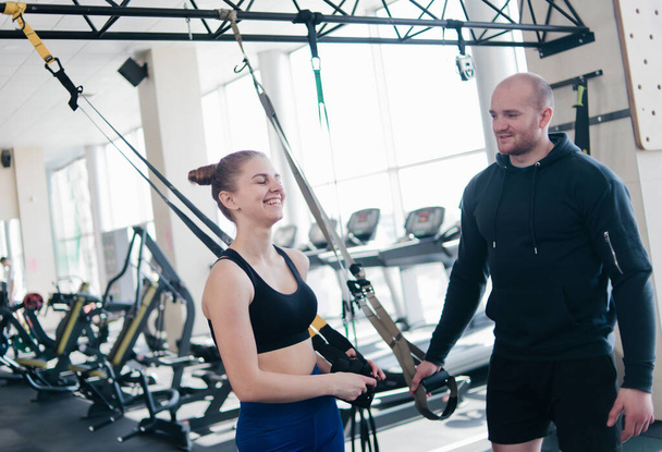 Happy fit woman and man talking during a break from exercise with fitness straps - Fotografie, Obrázek