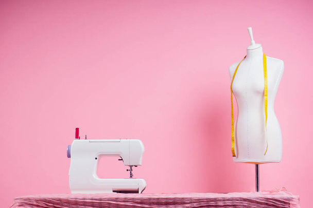 sewing pattern,sewing machine and maniken in studio pink background.seamstress curve template. tailor creates a collection outfits sews clothes in workshop. young woman designer clothes notes ideas - Φωτογραφία, εικόνα