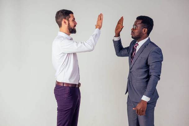 Two confident business men talking high five teamwork international company good deal.afro american and european man in studio on white background - Foto, immagini