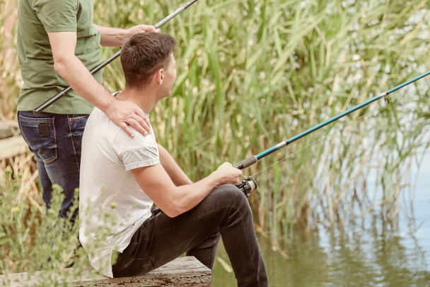 Jeune homme et son père pêchant sur la rivière
 - Photo, image