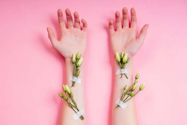 Nude manicure.Natural freshness and youth girl hands ,hand cosmetics with white rose flower adhesive plaster .Fashion woman hand with flowers and leaves,herbal skin care pink background studio shot - Photo, image